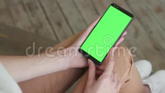 家中年轻女性移动智能手机的绿色屏幕视频的预览图
