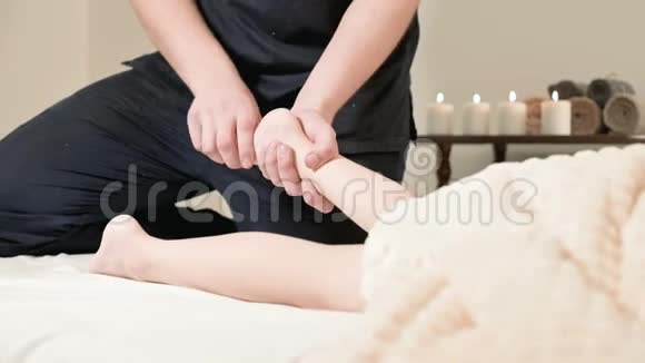 男理疗师按摩师为躺在按摩床上的小孩做一个舒缓足部按摩视频的预览图