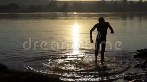 日落时分快乐的年轻人在湖中跳舞视频的预览图