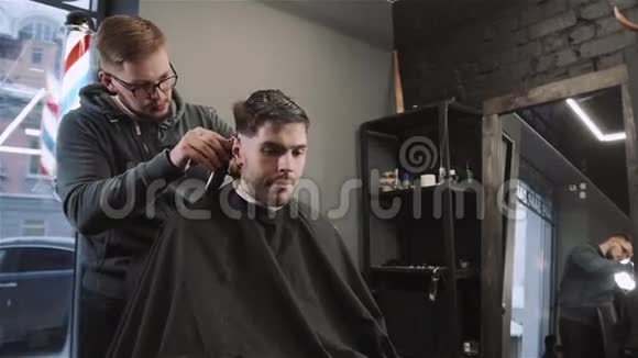帅哥为理发店的黑发男子理发现代发型师特写视频的预览图