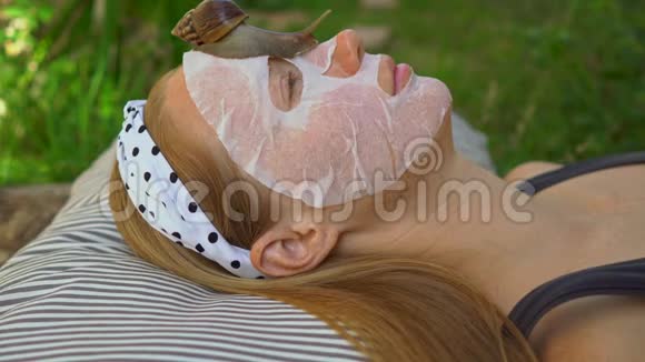 年轻女人用蜗牛粘液做面膜在面具上爬行的蜗牛视频的预览图