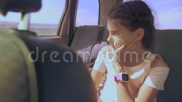 悲伤的女孩无聊地坐在后座的车里小女孩在车里无聊长途旅行视频的预览图