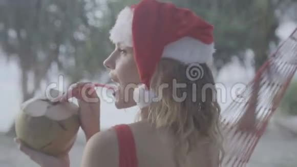海滩上戴圣诞帽的女人视频的预览图