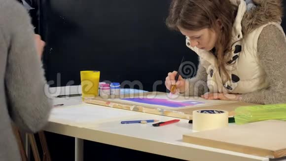 两名成年女子在艺术学校用彩色丙烯酸颜料作画视频的预览图