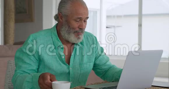成熟的男人在家里用笔记本电脑视频的预览图