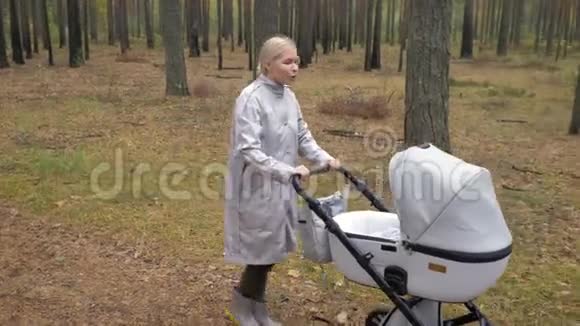 年轻可爱的妈妈带着婴儿车在公园散步视频的预览图