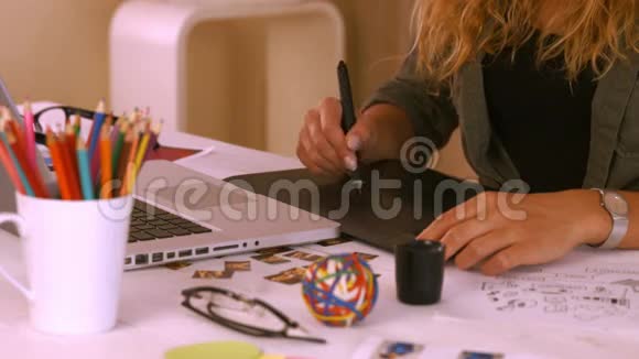 平面设计师在她的办公桌上使用数字化视频的预览图