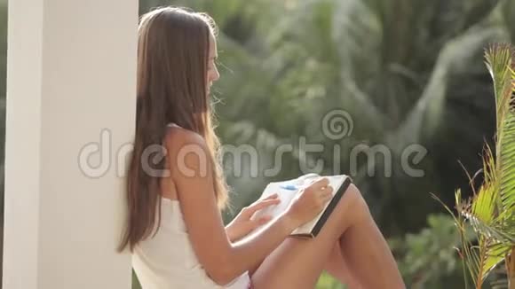 女人坐在阳台上写日记背景是花园视频的预览图