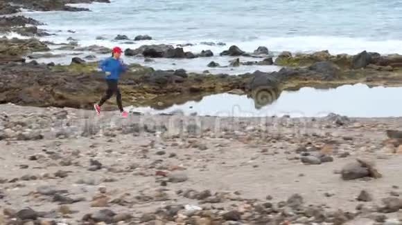 女人沿着海洋的石岸奔跑健康的生活方式视频的预览图