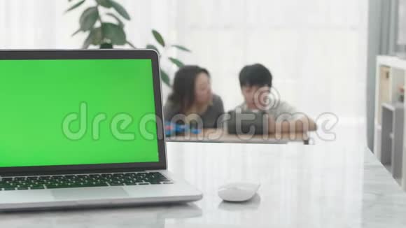 客厅的桌子上有一台显示绿色彩色键屏幕的笔记本电脑视频的预览图