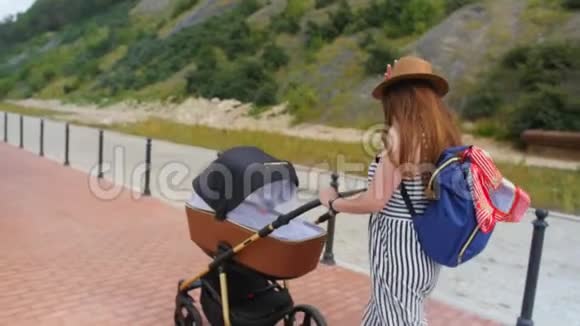 快乐的年轻母亲带着婴儿车在长廊散步家庭母性和人的概念有婴儿的幸福母亲视频的预览图