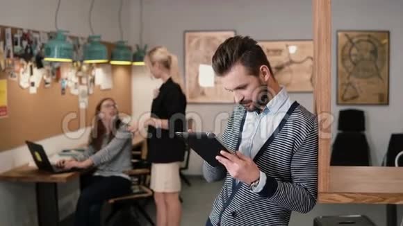 年轻英俊的胡子男在现代创业办公室使用触摸屏平板电脑视频的预览图