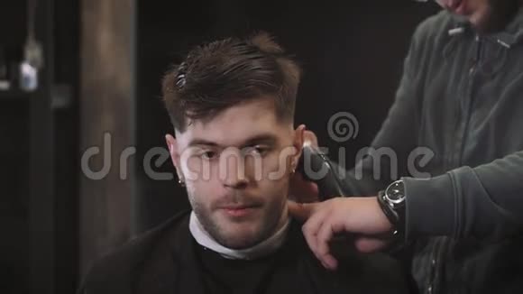 帅哥为理发店的黑发男子理发现代发型师特写视频的预览图