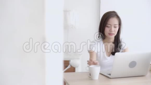 美丽的年轻自由职业亚洲女性微笑着工作在办公桌办公室配有专业电脑视频的预览图
