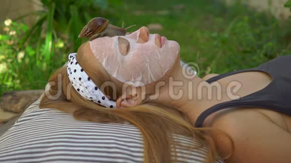 年轻女人用蜗牛粘液做面膜在面具上爬行的蜗牛视频的预览图