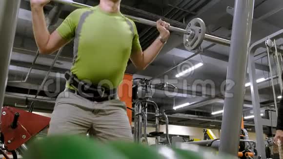 这个超重的人是用一个重量盘作为杠铃的蹲健身训练健康生活方式视频的预览图