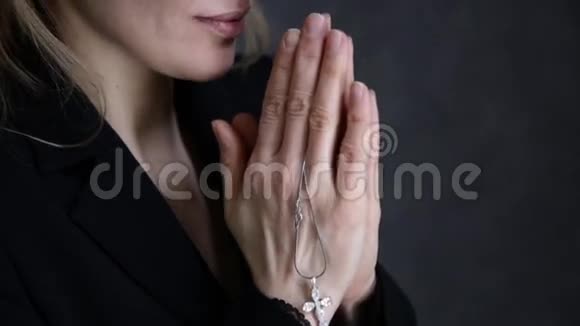 年轻女子在祈祷特写女性手拿着十字架的链子视频的预览图