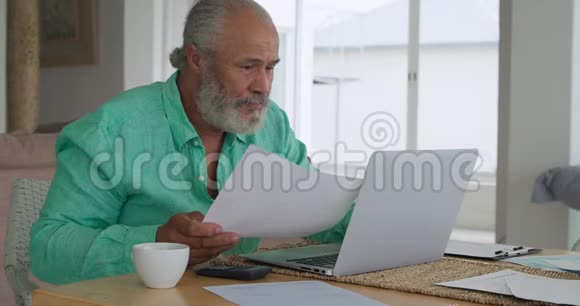 成熟的男人在家里用笔记本电脑视频的预览图