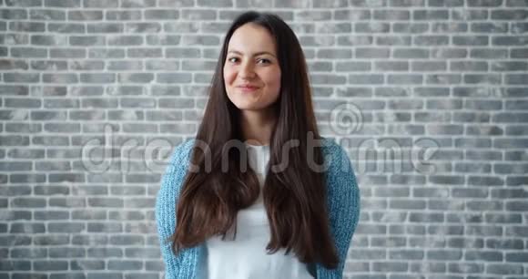 砖墙背景上美丽的年轻女子微笑的肖像视频的预览图