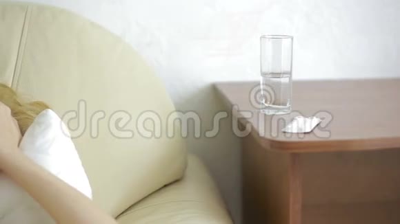 生病的女人躺在床上药丸和一杯水喝药片止痛药视频的预览图