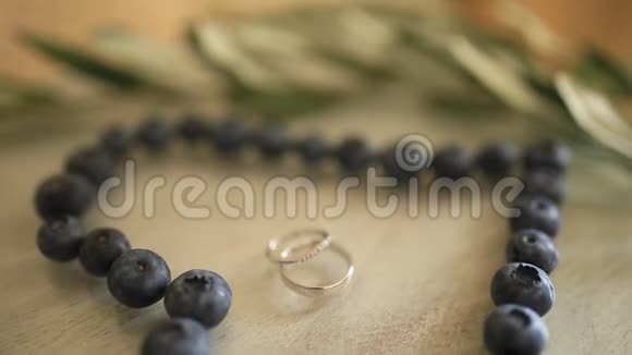 婚礼戒指在一个蓝莓的中心在一张桌子上旁边是一个视频的预览图