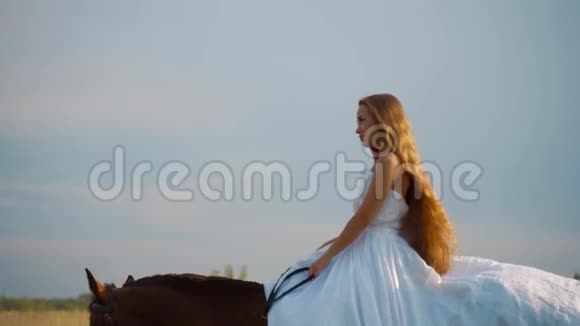 穿着白色连衣裙的女孩骑着马新娘骑马在田野里视频的预览图
