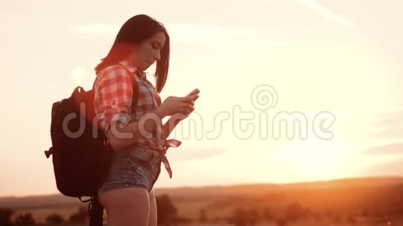 hipsterhiker剪影女孩漫游者在手机智能手机上搜索位置导航视频的预览图