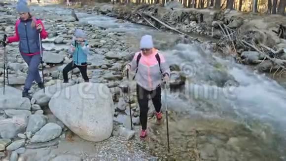 女人在大自然中行走靠近山河女孩和孩子使用跋涉棒和北欧杆视频的预览图