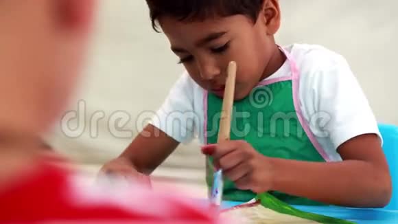 可爱的小男孩在教室的桌子上画画视频的预览图