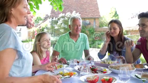 坐在户外围着桌子吃饭的多代家庭视频的预览图