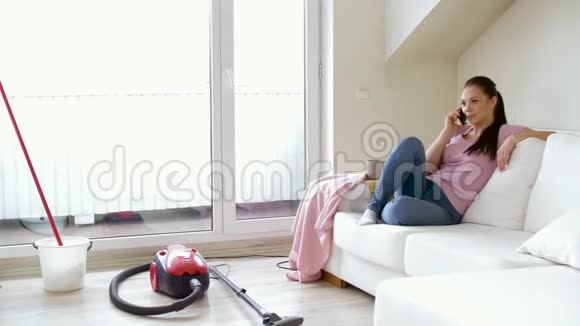 打扫完屋子后一个女人用智能手机打电话视频的预览图