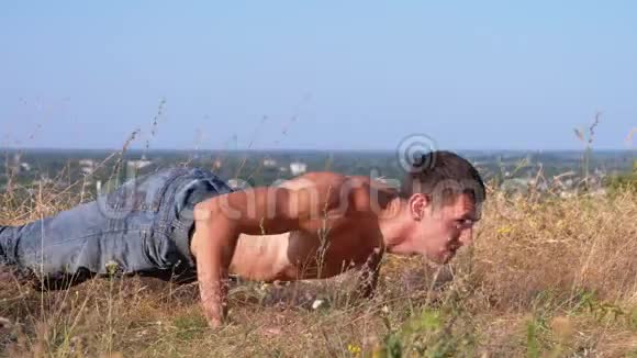 一个身体裸露的年轻运动员在大自然中做俯卧撑视频的预览图