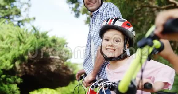 爸爸和孩子们骑着自行车站在公园里视频的预览图