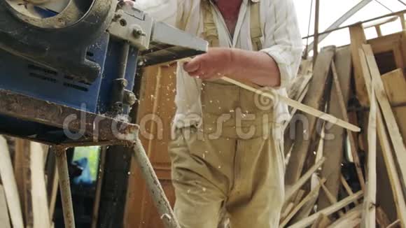 一个年长的木匠在一个小作坊里用木头做一只小船视频的预览图