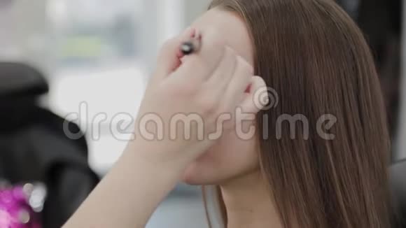 专业化妆师女人在美容院给一个漂亮女孩化妆视频的预览图
