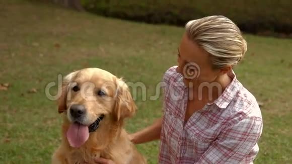 快乐的金发女人和她的狗在公园里视频的预览图