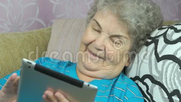 老年妇女在室内持有数码平板电脑视频的预览图