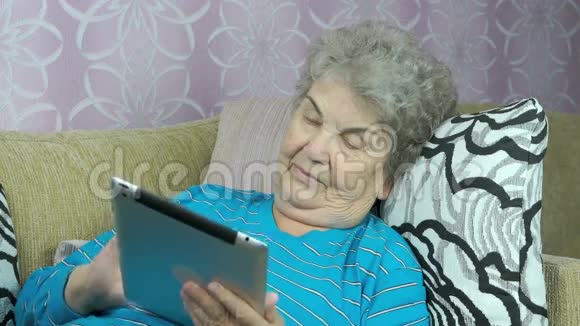 老年妇女在室内持有数码平板电脑视频的预览图