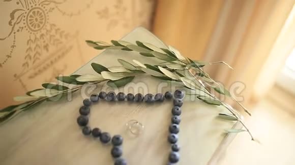 婚礼戒指在一个蓝莓的中心在一张桌子上旁边是一个视频的预览图