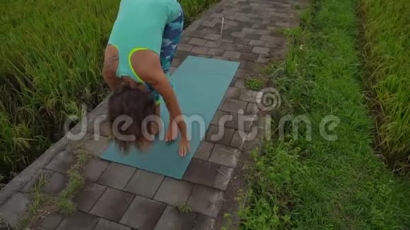 一个年轻女子在美丽的稻田里练习瑜伽的慢动作稳定镜头视频的预览图