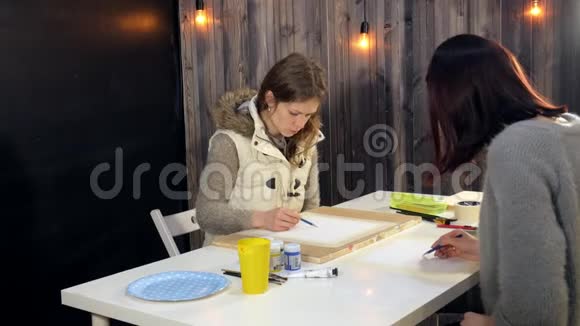 两名成年女子在艺术学校用彩色丙烯酸颜料作画视频的预览图