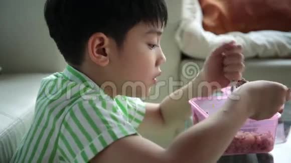亚洲小孩坐在餐桌前在家吃饭视频的预览图