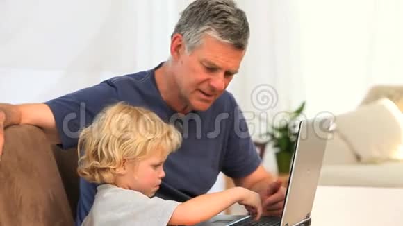 带着祖父看笔记本电脑的男孩视频的预览图