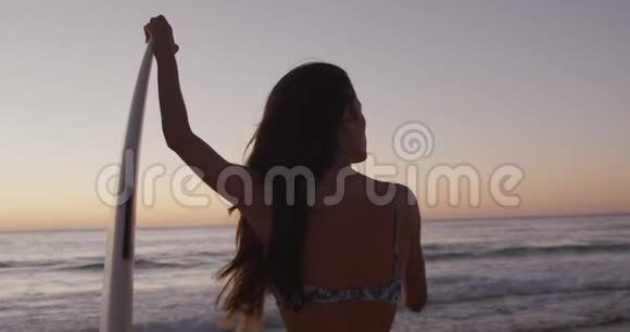 日落时分在海滩上放松的年轻女子视频的预览图