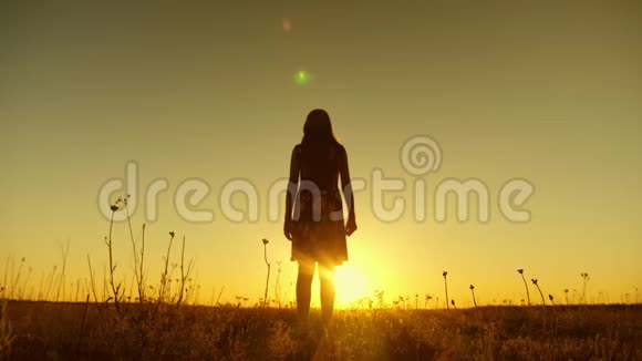 在一个温暖的夜晚快乐的女孩在金色的太阳日落时跳得很高慢动作视频的预览图