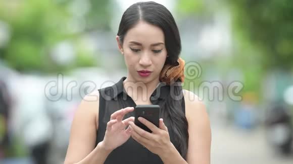 年轻漂亮的亚洲女商人在户外大街上用电话视频的预览图