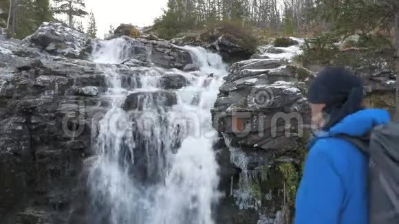 一个人带着背包沿着山区路线旅行他到达了美丽的瀑布并在一个视频的预览图