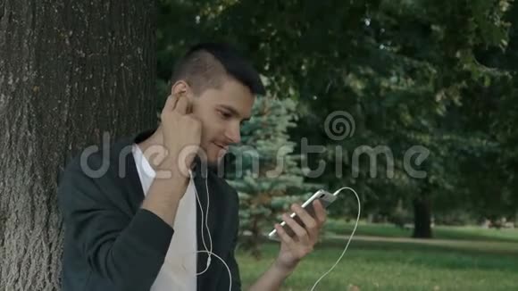 年轻的帅哥用耳机听音乐视频的预览图