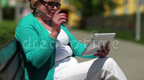 女人坐在长凳上通过平板电脑交流视频的预览图