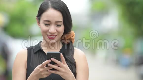 年轻漂亮的亚洲女商人在户外大街上用电话视频的预览图